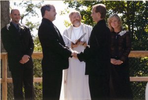 Outdoor wedding ceremony of two grooms and the minister