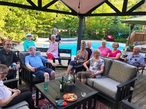 Twelve people enjoy a summer garden party around a swimming pool