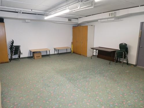 Open carpeted room. Tables and chairs are placed around the walls.