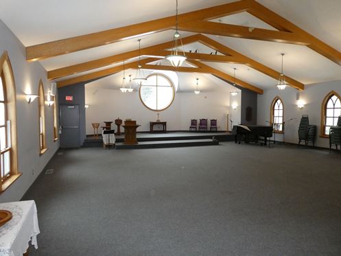 Photo taken of large church sanctuary. Chairs are stacked and room is empty.